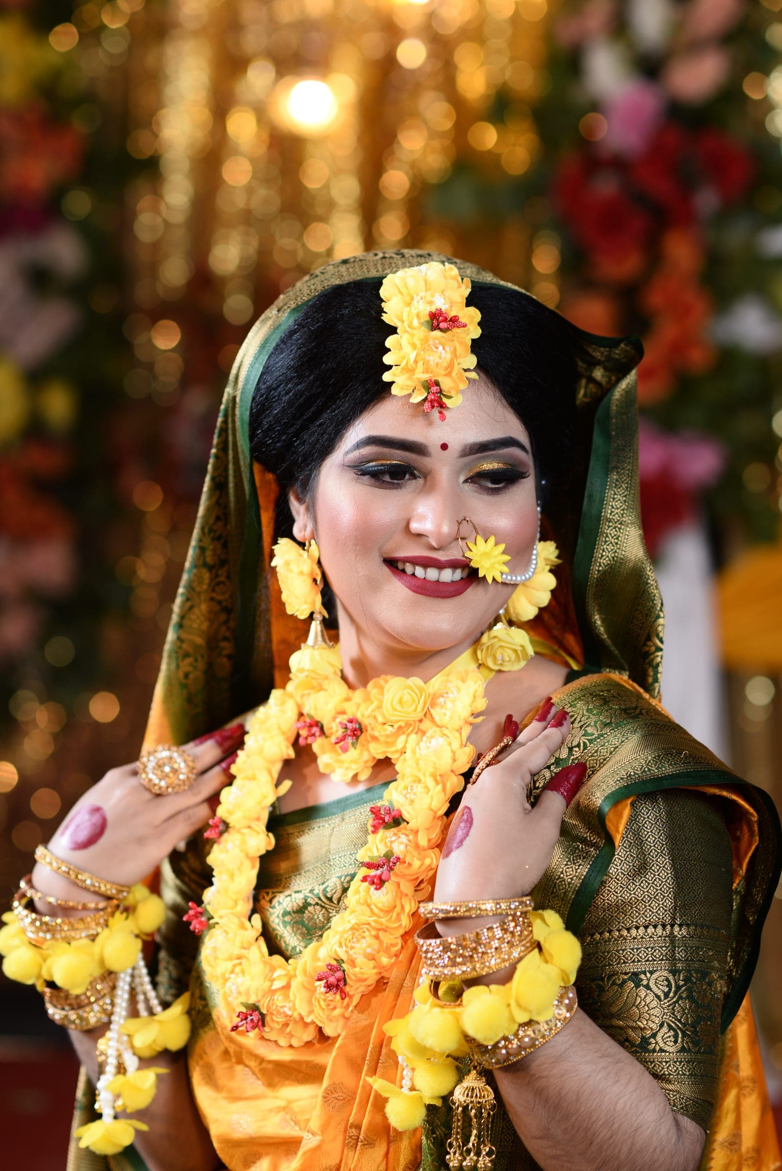 Smiling bride wearing marigold holud jewellery and a green saree