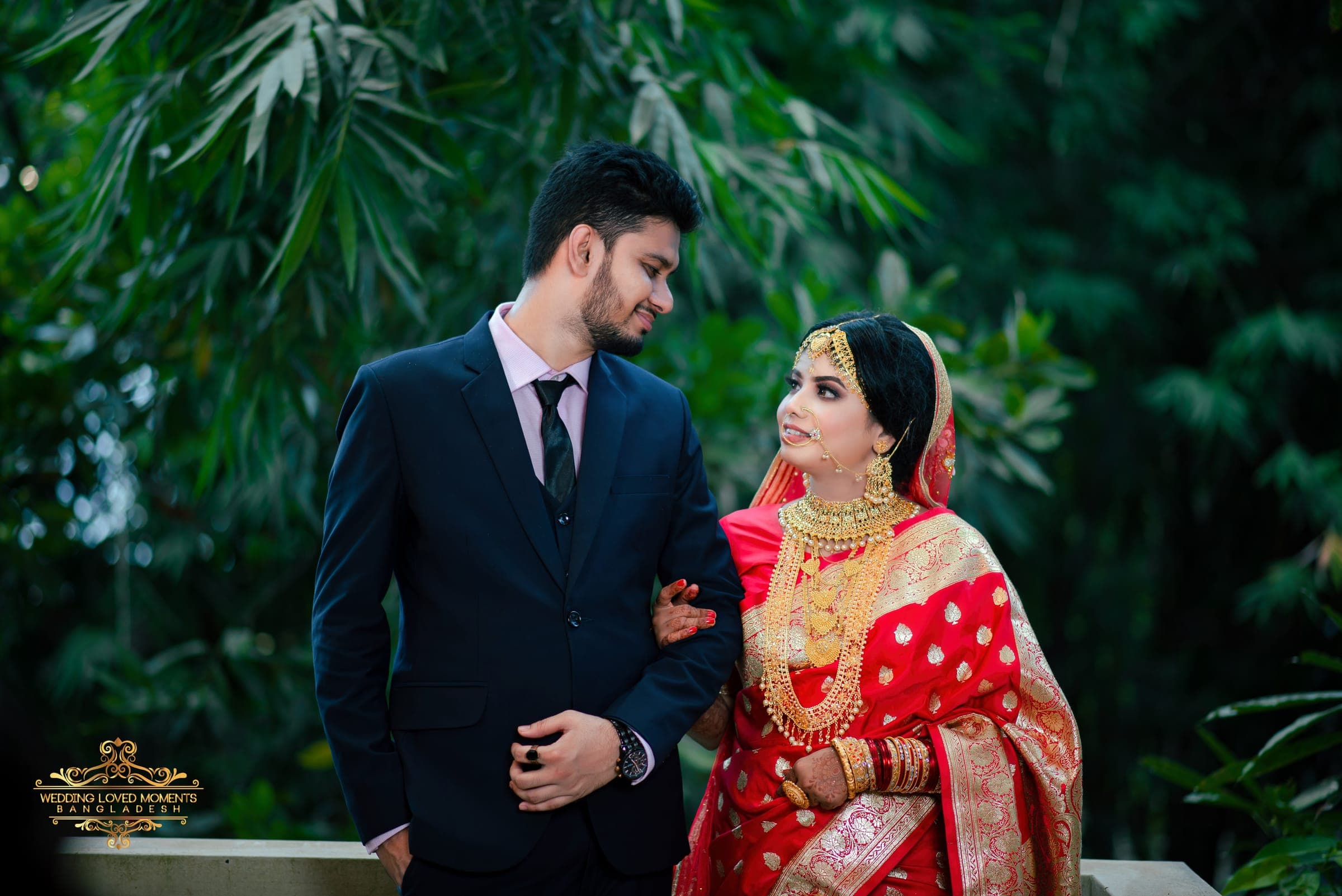 Wide portrait of a couple in a garden, the bride turning to smile at the groom